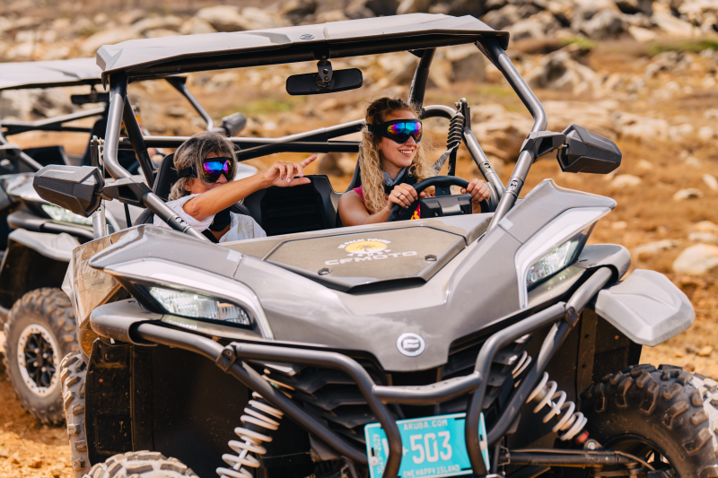 Two people driving an off-road vehicle on a rocky terrain.