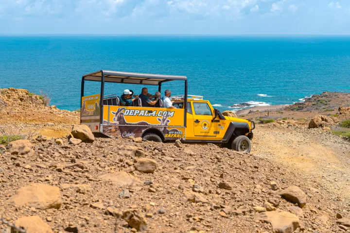 a tractor on a rocky beach next to a body of water